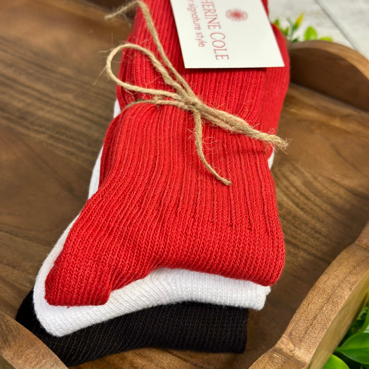 Red sock with a white sole and black heel on a wooden surface, featuring a Catherine COLE' tag.