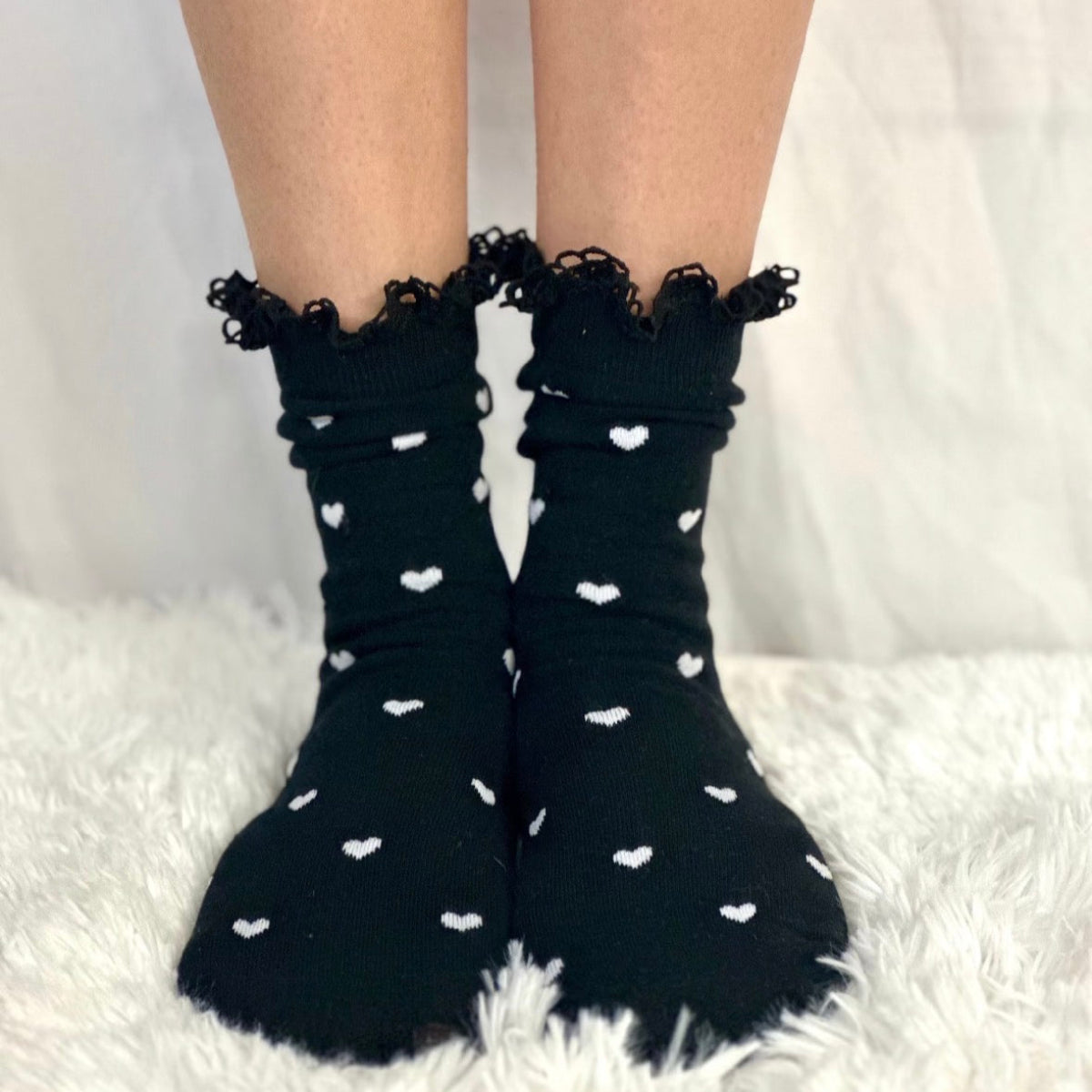 Black socks with white heart patterns and lace trim on a white background Catherine cole