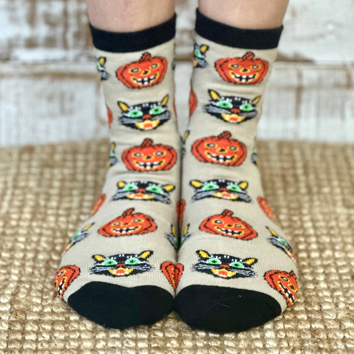 Halloween-themed socks with pumpkins and cats on a neutral background
