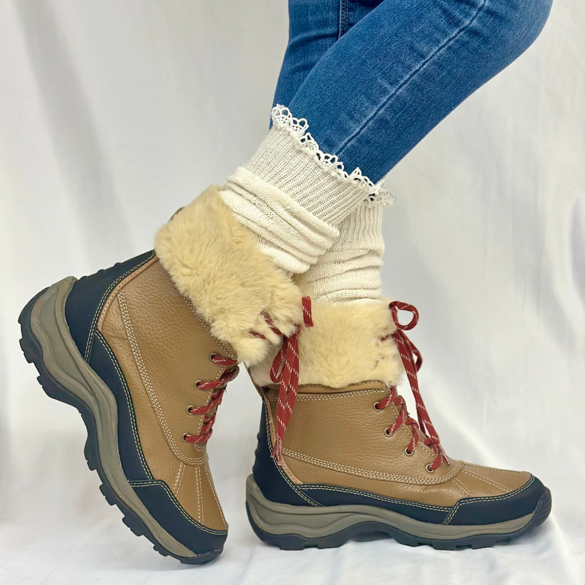 Tan and navy winter boots with fur lining worn by a person on a white , MOUNTAIN lace knee boot socks - naturalbackground