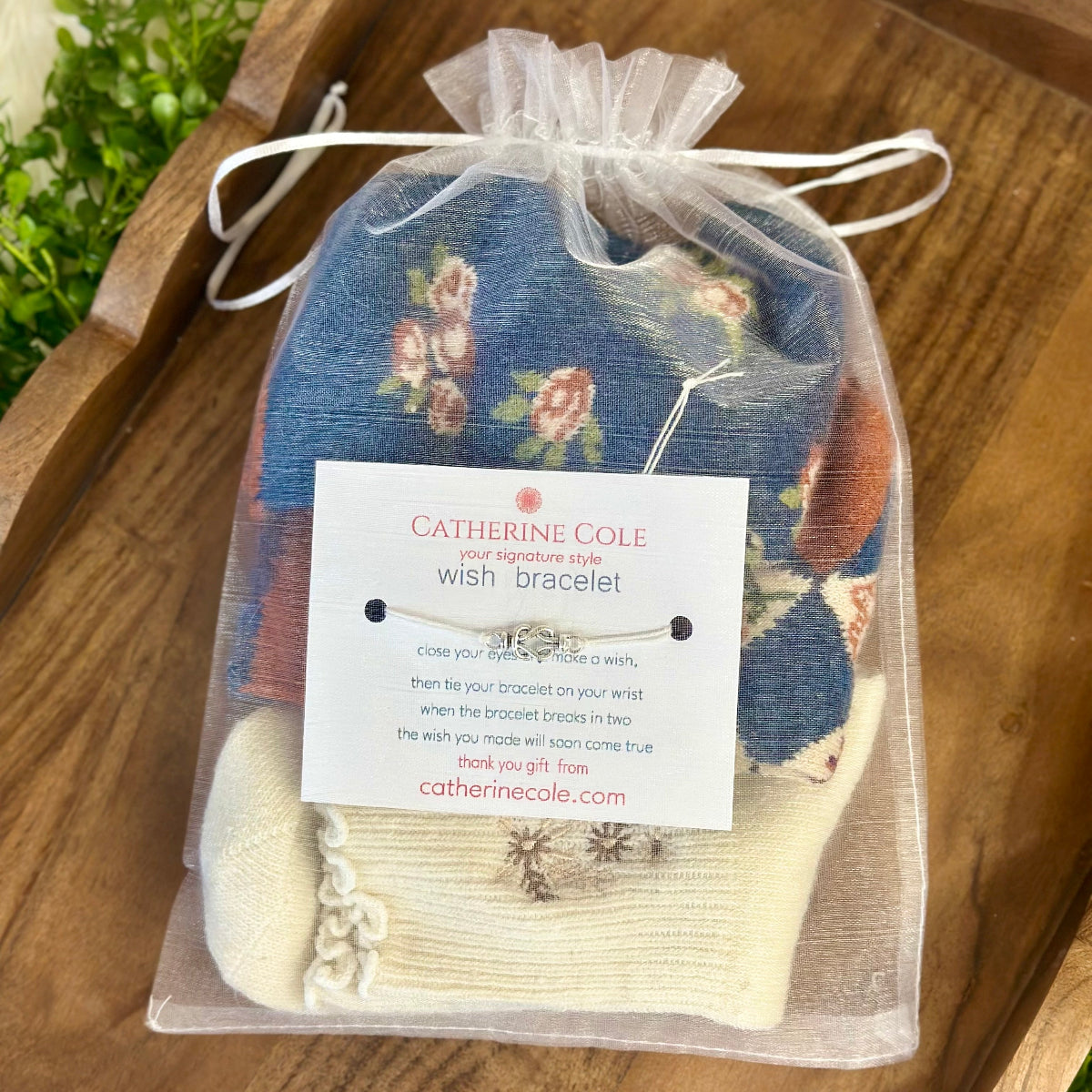 Catherine Cole wish bracelet in a sheer bag on a wooden surface