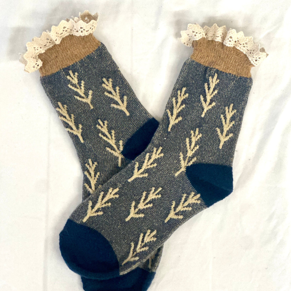 Pair of socks with leaf pattern and lace trim on a white background, TWIGS lace topped socks - indigo