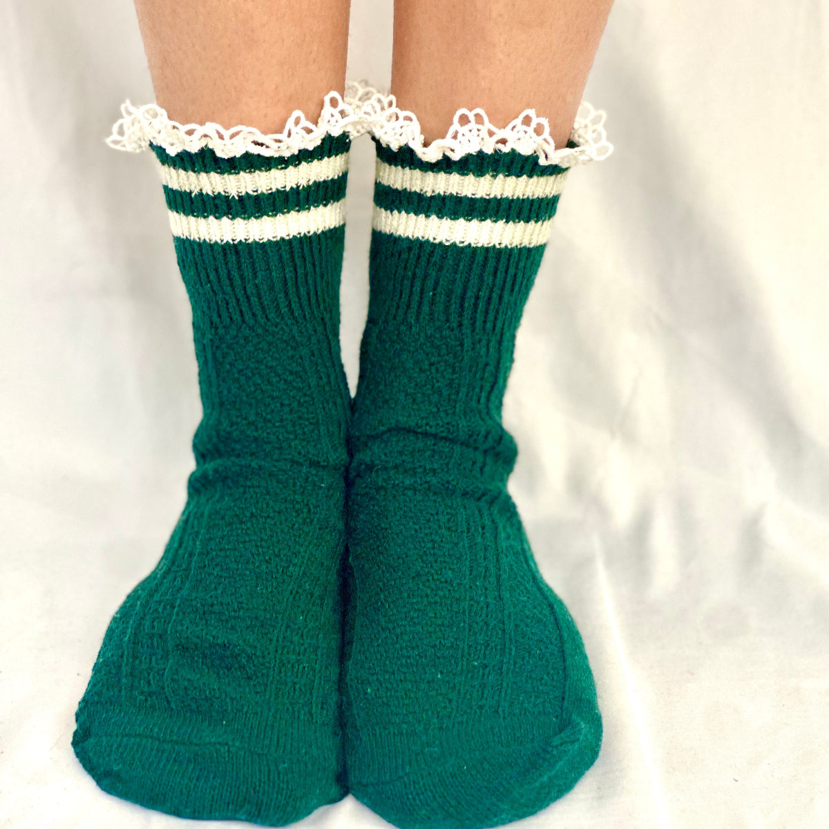 Green socks with white lace trim on a neutral background,