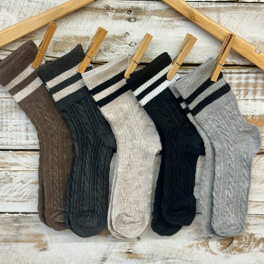 Set of six pairs of socks hanging on a wooden rack against a rustic wooden background.