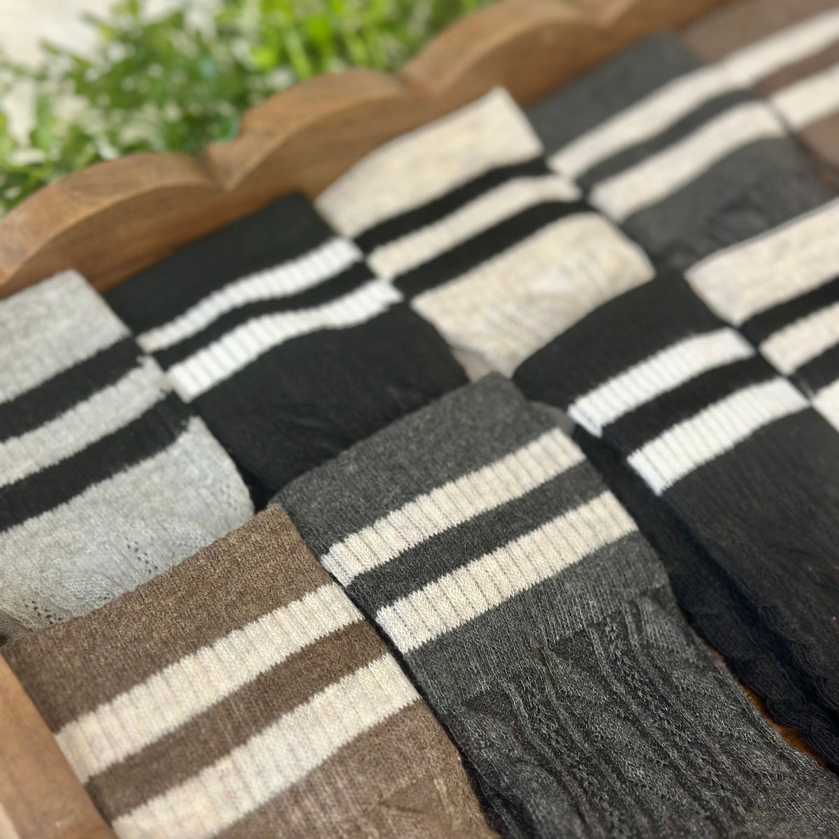 Collection of striped socks in various colors on a wooden surface with a blurred natural background.