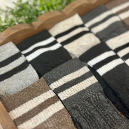 Collection of striped socks in various colors on a wooden surface with a blurred natural background.