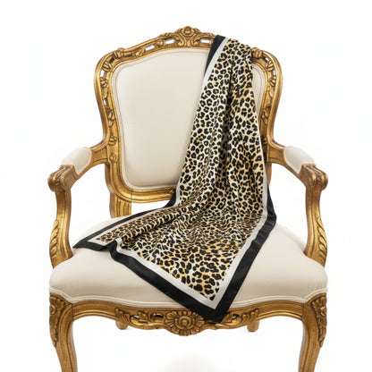 Leopard print blanket draped over a decorative chair with gold frame and white cushion by Catherine cole