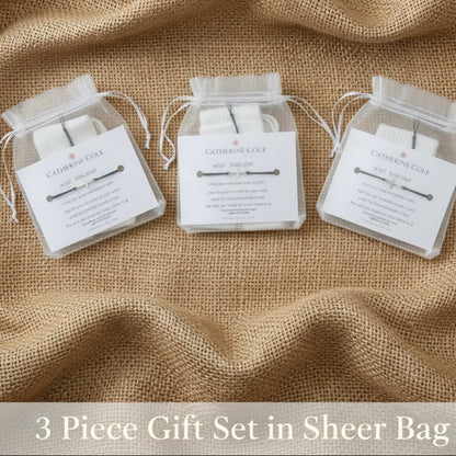 A pair of silver-toned barbell earrings in a clear plastic bag with a white paper insert card labeled 'CATHEDRAL COALE'.