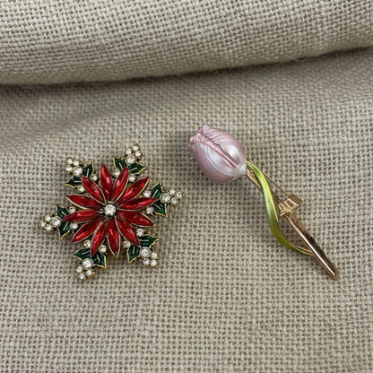 Red snowflake-shaped brooch with gold accents on a light gray , Black Brocade Evening Bag with Interchangeable Brooches – Set of 2 Pins background