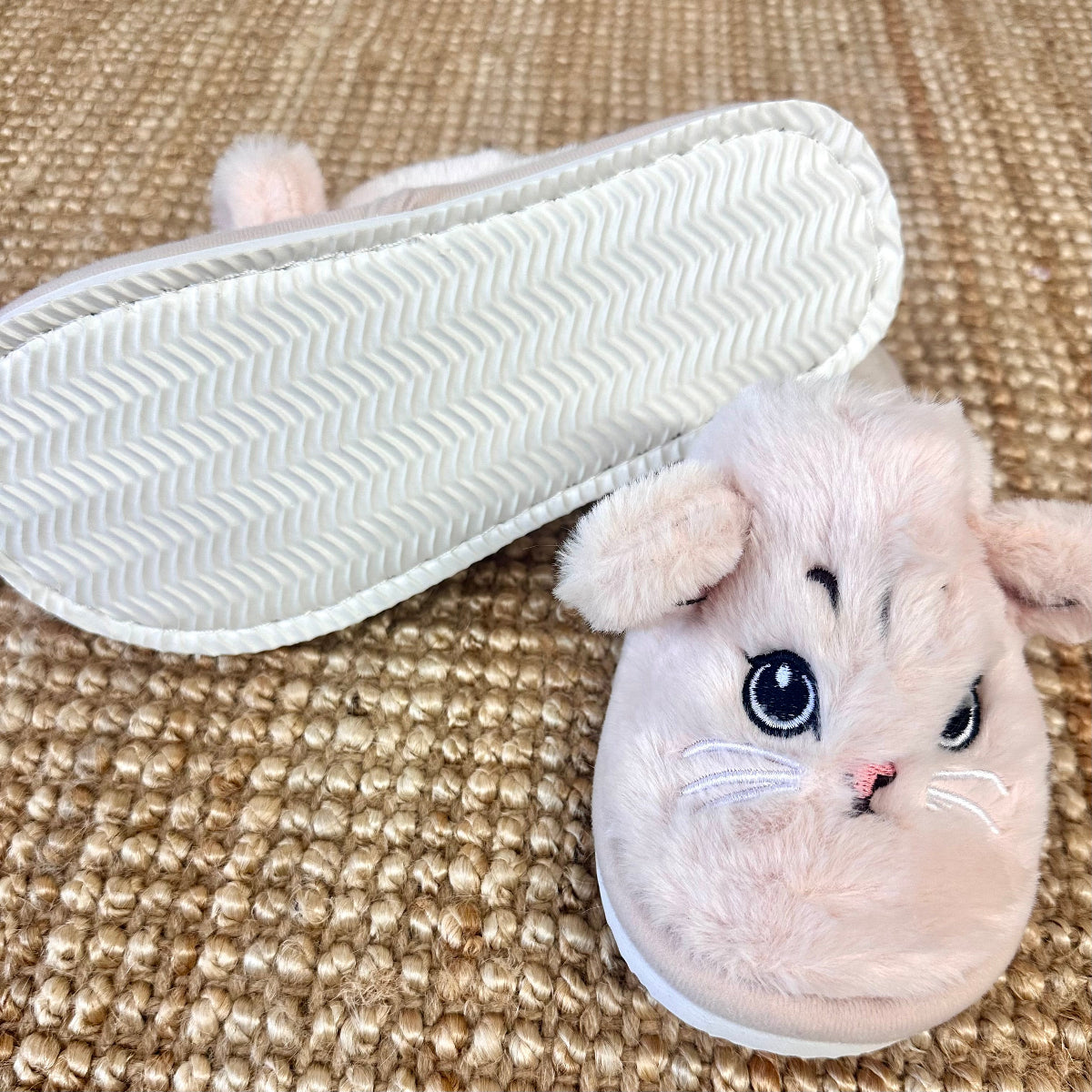 Fluffy white slipper with cat face design on a textured surface by Catherine cole
