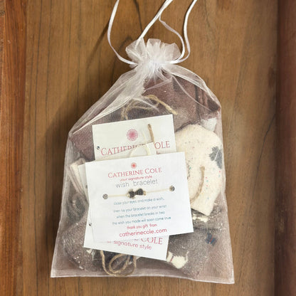 Gift bag with 'Catherine Cole' jewelry items and packaging on a wooden surface
