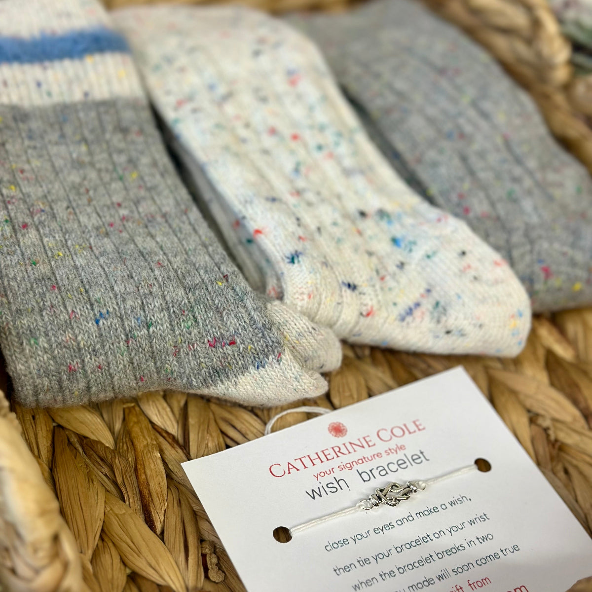 Three pairs of socks with a 'Catherine Cole' bracelet on a woven surface, Cozy grey mix patterned socks - 3 pair gift set + wish bracelet