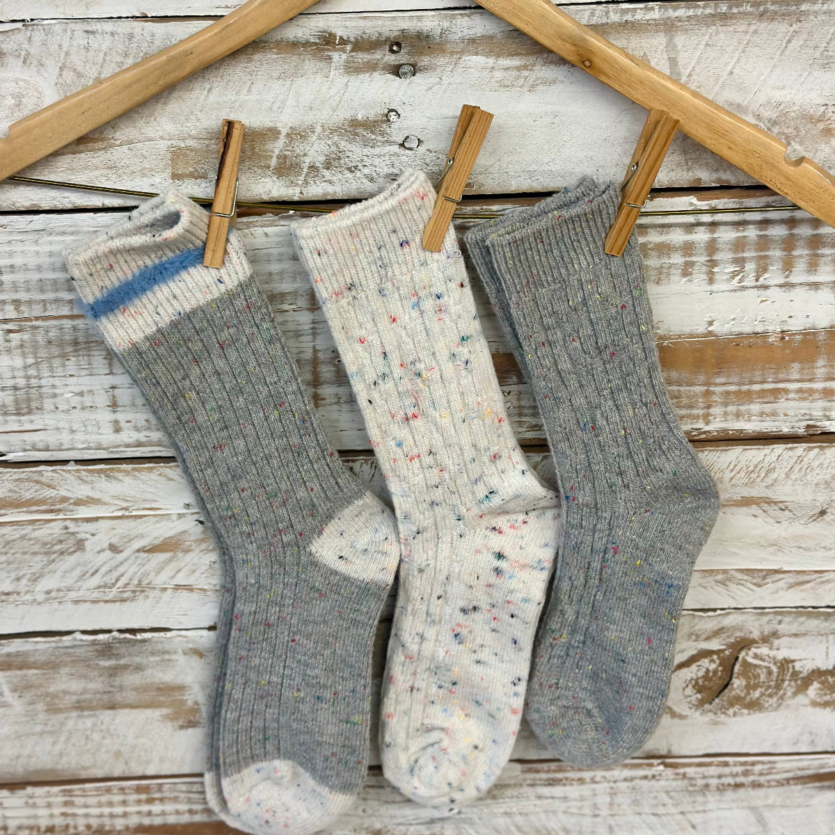 Three pairs of socks hanging on a wooden rack against a rustic wooden background., Cozy grey mix patterned socks - 3 pair gift set + wish bracelet