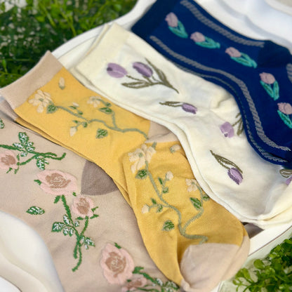 Set of embroidered socks in various colors with floral patterns on a grassy background.  Floral Flower Ankle Socks 4-Pack Bundle with Wish Bracelet - Women's 6-9