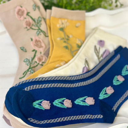 Set of floral embroidered socks in various colors on a white surface.  Floral Flower Ankle Socks 4-Pack Bundle with Wish Bracelet - Women's 6-9