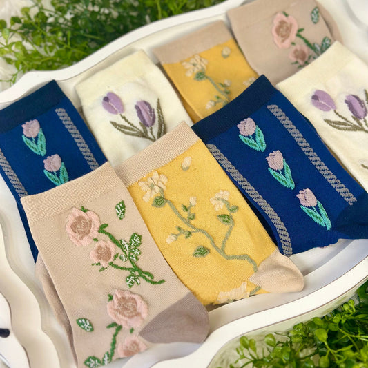 Set of floral embroidered socks in various colors arranged in a white dish.  Floral Flower Ankle Socks 4-Pack Bundle with Wish Bracelet - Women's 6-9