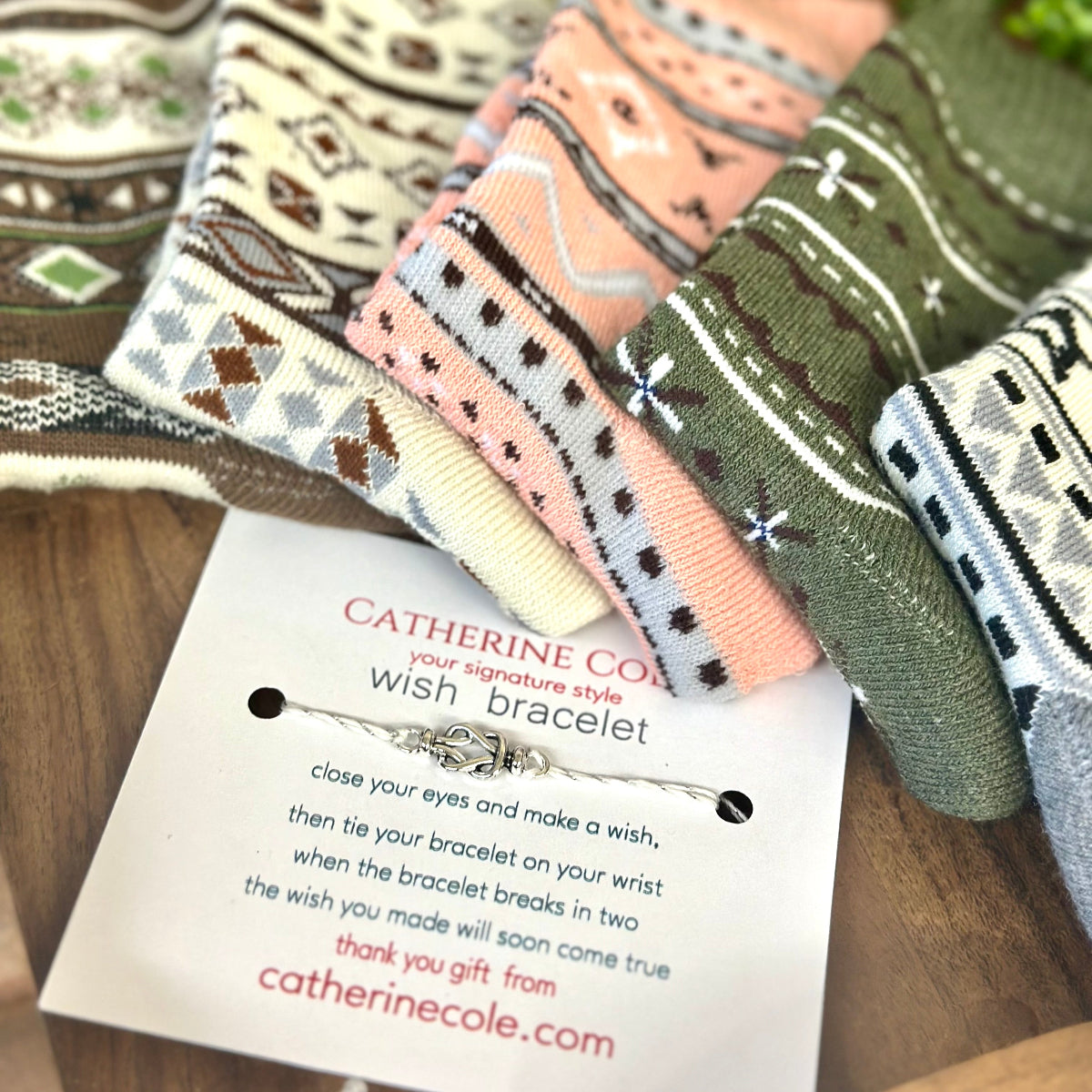 Colorful patterned bracelets on a wooden surface with a Catherine Cole label.  Geometric Patterned Ankle Socks 5-Pack Bundle with Wish Bracelet - Women's 6-9