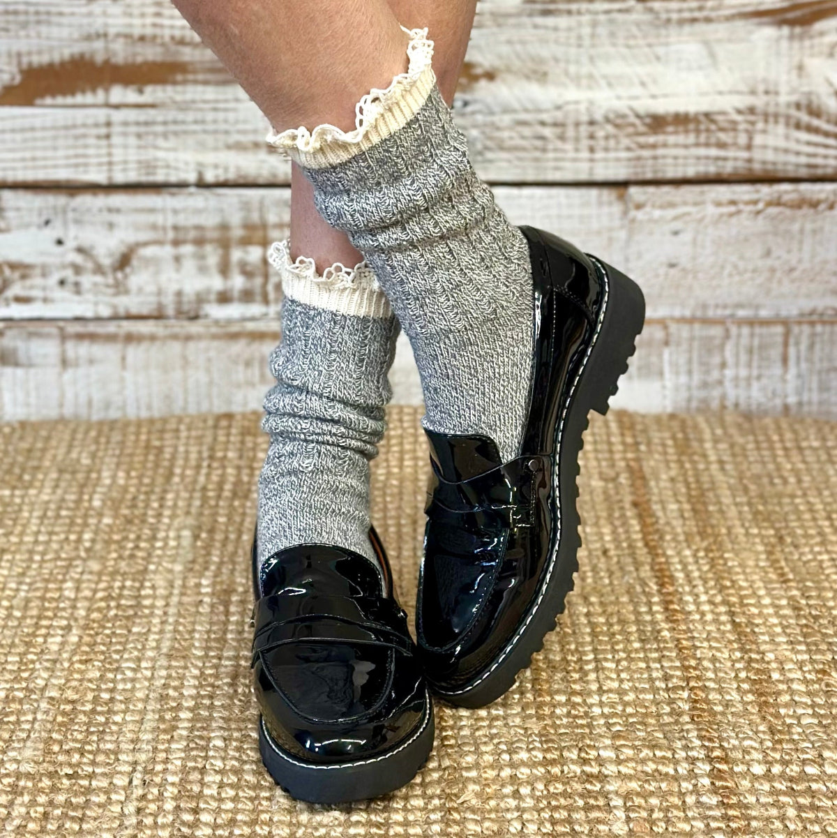 Person wearing black platform shoes with gray socks and white lace trim on a wooden floor.  ORGANIC Lace Boot Crew Socks Women's - Grey | Made in USA