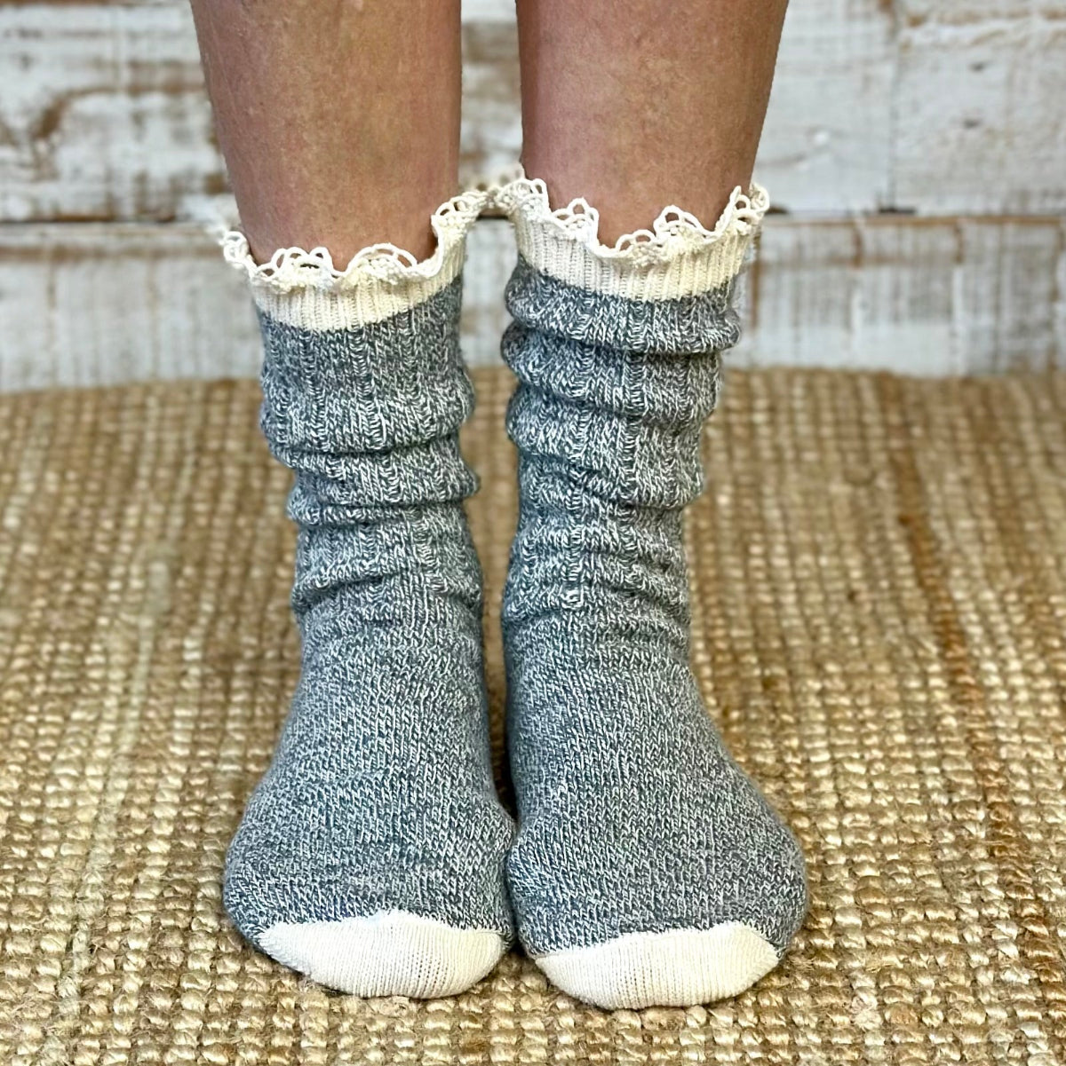 Gray socks with white lace trim worn by a person on a textured surface.  ORGANIC Lace Boot Crew Socks Women's - Grey | Made in USA