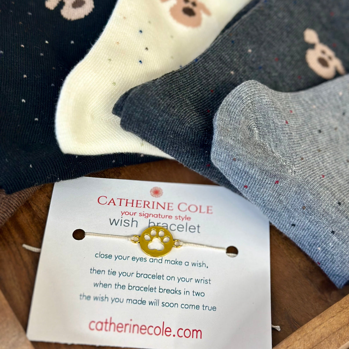 Four pairs of socks with a Catherine Cole bracelet on a wooden surface PAW-SOME 5-Pack Dog Novelty Socks + Paw Wish Bracelet | Women's 6-9