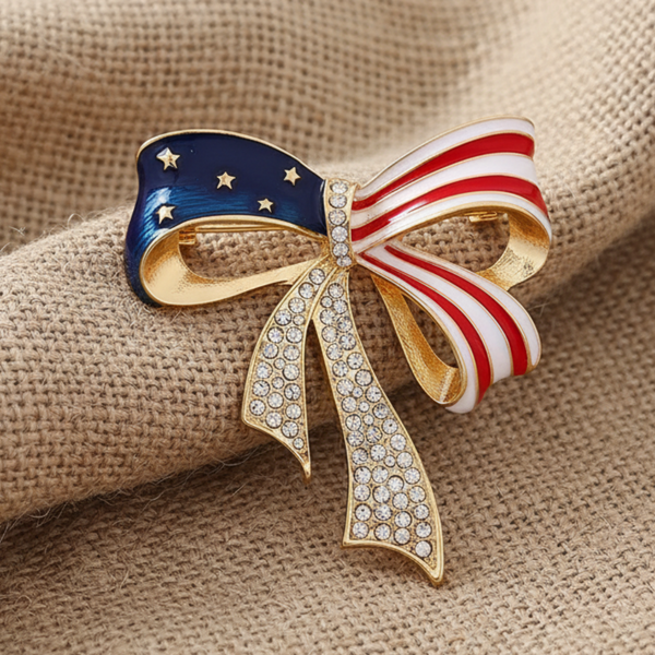 Brooch with American flag design and gold accents on a white background,  Patriotic rhinestone bow brooch pin by Catherine Cole
