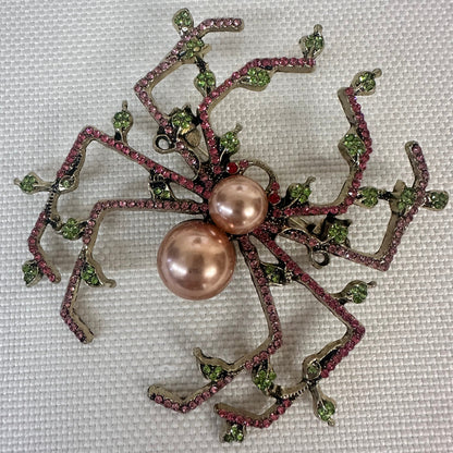 Decorative brooch with pink pearls and green gemstones on a textured background.  Pearl & Crystal Spider Brooch Pin - Charlotte's Garden Vintage Jewelry