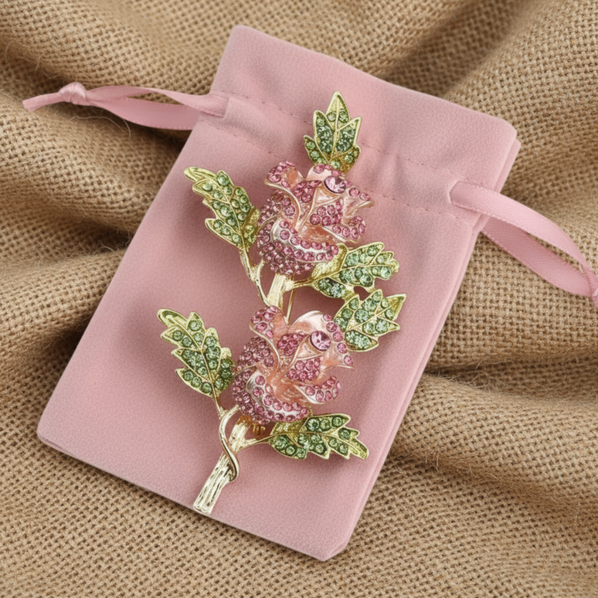 Decorative brooch with pink and green gemstones on a pink velvet pouch.  Pink Double Rose Crystal Brooch Pin 4" | Rhinestone Flower Brooch