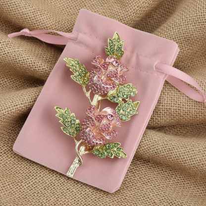 Decorative brooch with pink and green gemstones on a pink velvet pouch.  Pink Double Rose Crystal Brooch Pin 4" | Rhinestone Flower Brooch