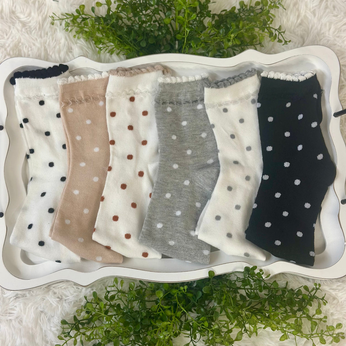 Set of polka dot socks in various colors on a decorative tray with a white background.