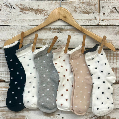 Set of polka dot socks on a wooden hanger against a rustic wooden background