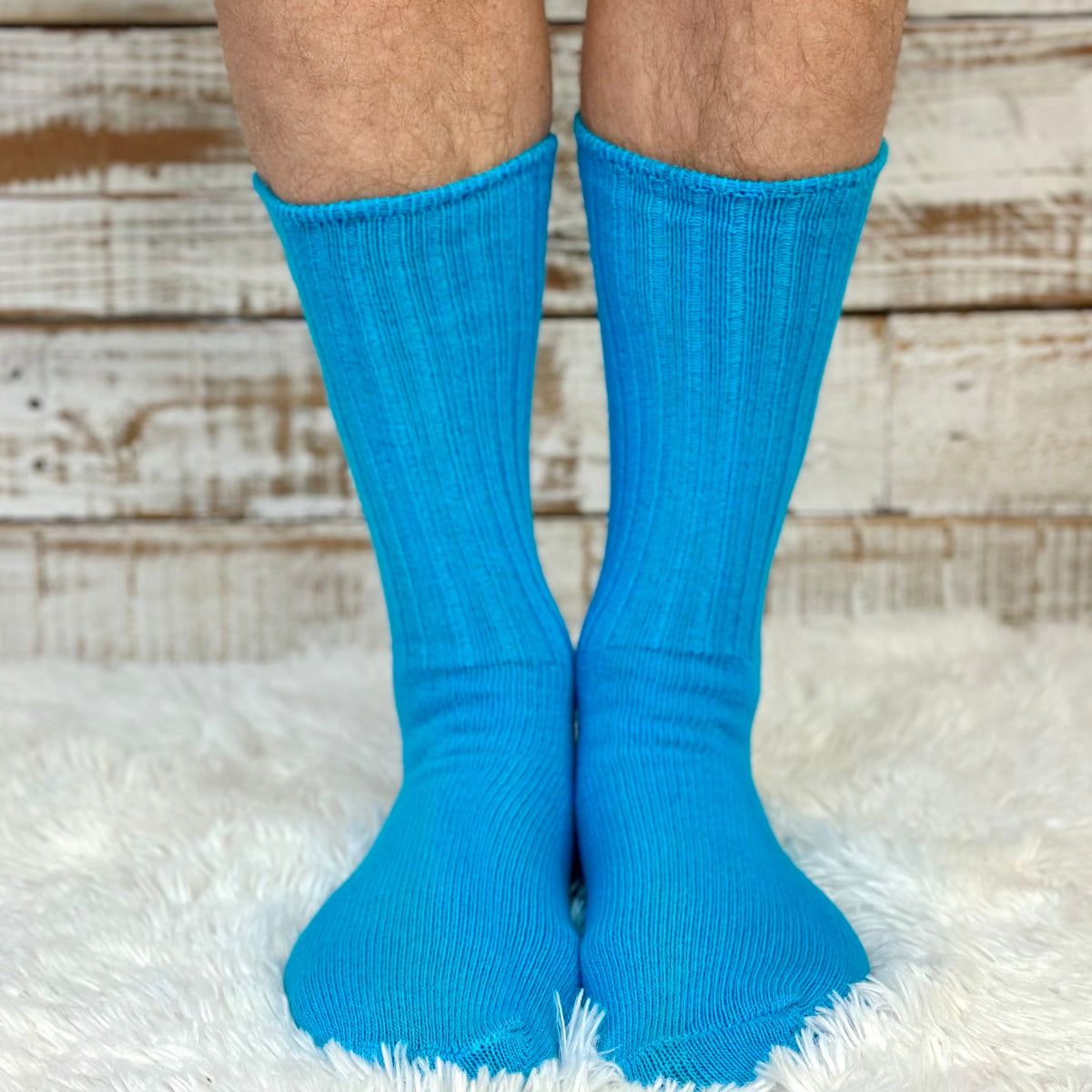 Blue socks worn on a person's feet with a wooden floor background