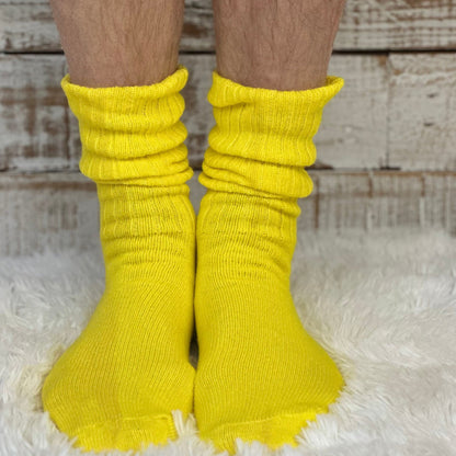 Yellow socks worn on feet with a wooden floor background