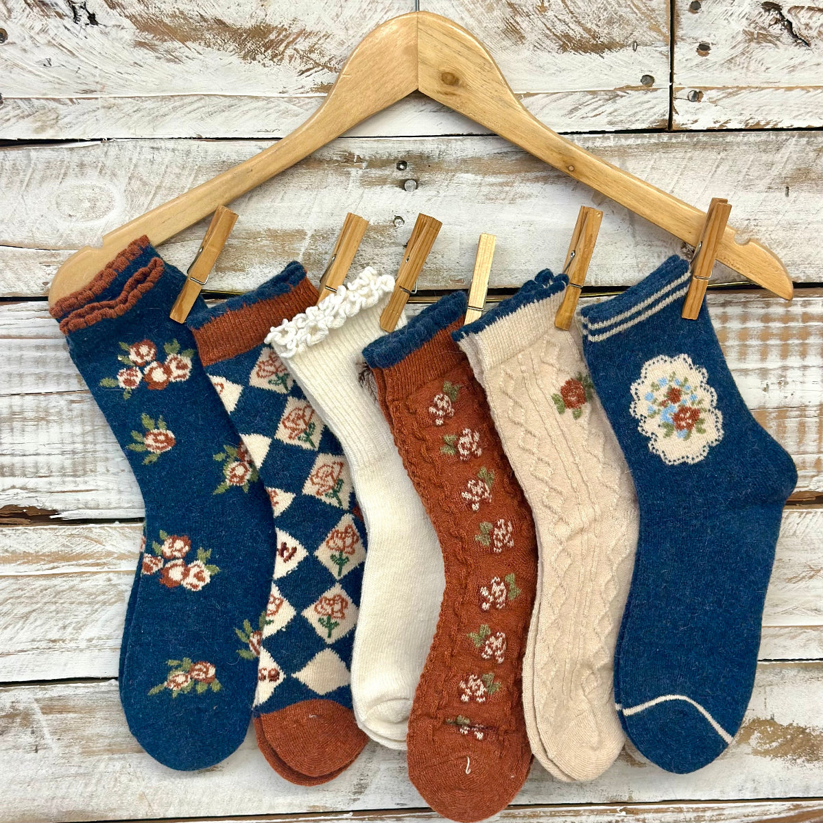 Set of patterned socks hanging on a wooden hanger against a rustic wooden background by Catherine cole
