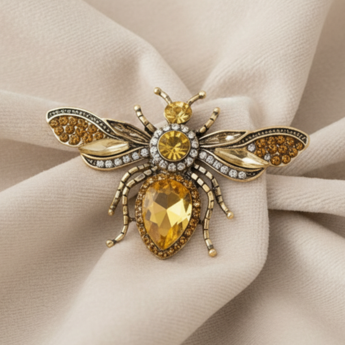 Gold bee-shaped brooch with gemstones on a white blazer