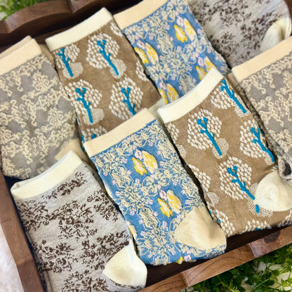 Set of patterned socks on a wooden surface with a natural background. Spring Floral Ankle Socks 4-Pack Bundle with Wish Bracelet - Women's 6-9
