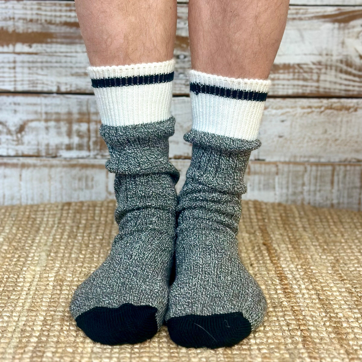 Gray socks with white tops and black toes worn by a person on a wooden floor.  Striped Marled Slouch Socks Unisex 10-14 - Salt & Pepper