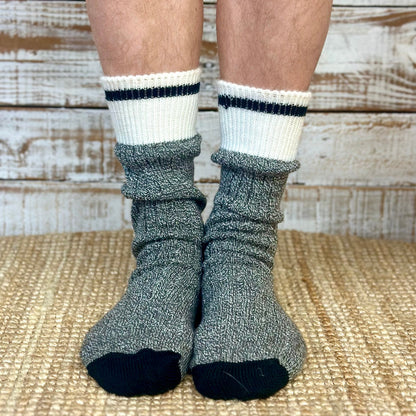 Gray socks with white tops and black toes worn by a person on a wooden floor.  Striped Marled Slouch Socks Unisex 10-14 - Salt & Pepper