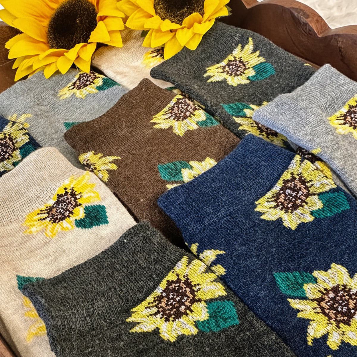 Set of sunflower-patterned socks in various colors on a wooden surface with sunflowers.  Sunflower Patterned Ankle Socks 5-Pack Bundle with Wish Bracelet - Women's 