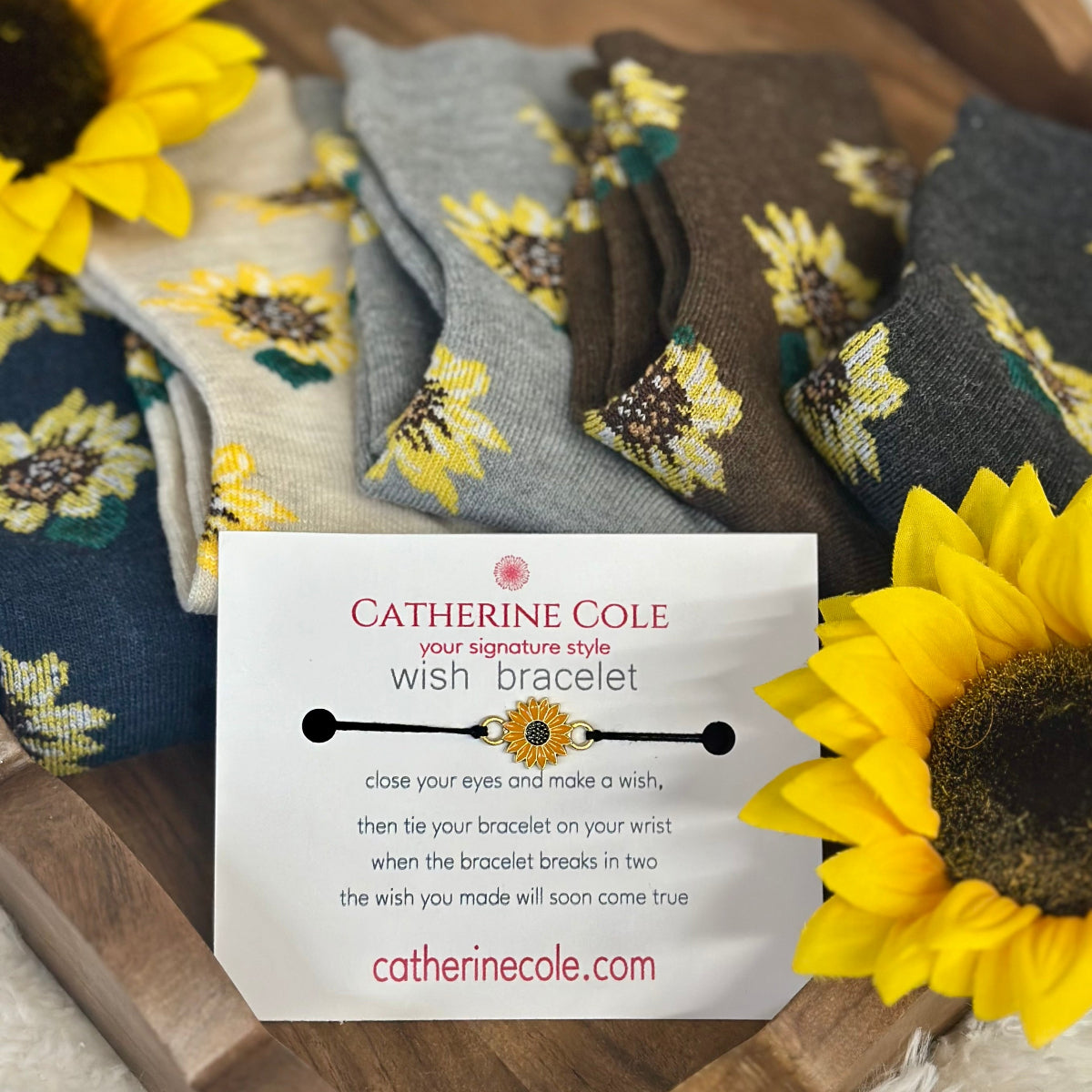 Sunflower-themed socks with a Catherine Cole wish bracelet card on a wooden surface.  Sunflower Patterned Ankle Socks 5-Pack Bundle with Wish Bracelet - Women's 