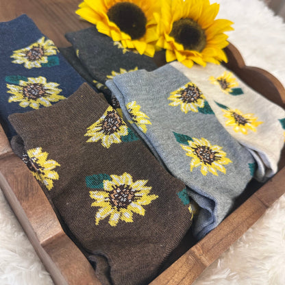 Sunflower-patterned socks in a wooden box with sunflowers on a fluffy white surface.  Sunflower Patterned Ankle Socks 5-Pack Bundle with Wish Bracelet - Women's 
