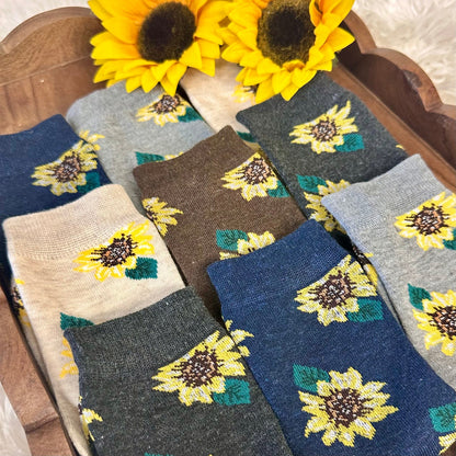 Sunflower-patterned socks in various colors on a wooden surface with sunflowers.  Sunflower Patterned Ankle Socks 5-Pack Bundle with Wish Bracelet - Women's 