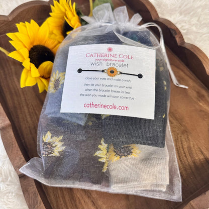 Catherine Cole wish bracelet packaging with a sunflower on a wooden surface