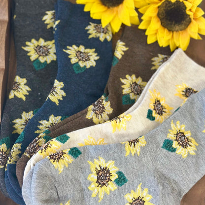 Sunflower-patterned socks in various colors on a wooden surface with sunflowers.  Sunflower Patterned Ankle Socks 5-Pack Bundle with Wish Bracelet - Women's 