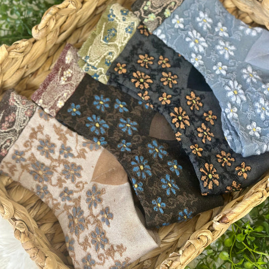 Collection of floral-patterned fabric swatches in a woven basket. Tapestry Patterned Ankle Socks 4-Pack Bundle with Wish Bracelet - Women's