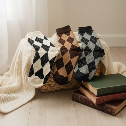 Three pairs of argyle socks in a basket with books on a wooden floor.