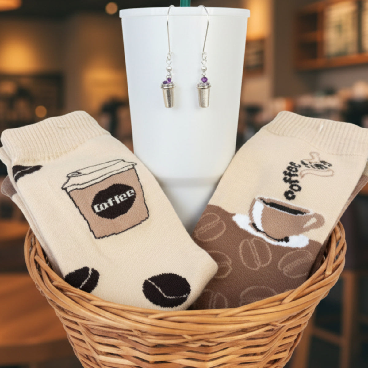 Pair of socks with coffee-themed design in a basket with a cup and earrings. The Coffee Lover Gift Set (2-Pack Socks + Coffee Cup Earrings)