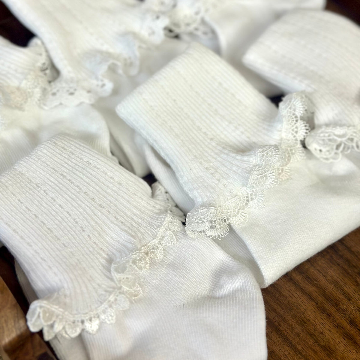 White socks with lace trim on a wooden surface. Valued priced 3 pair bundle assorted laces