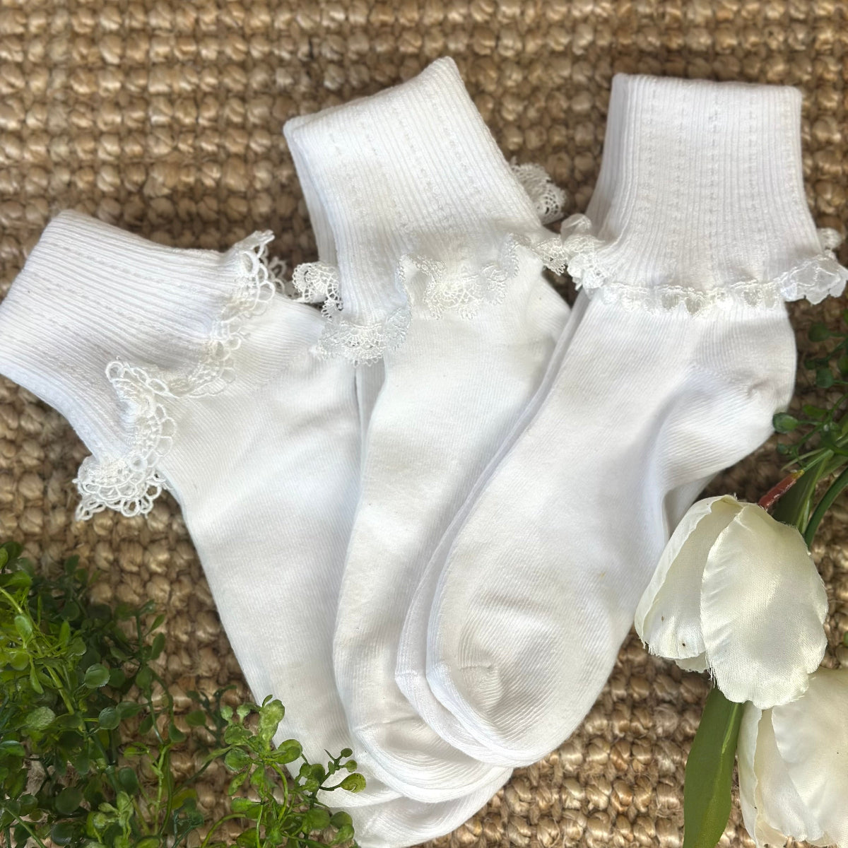 White socks with lace trim on a textured surface with flowers.  Valued priced 3 pair bundle assorted laces