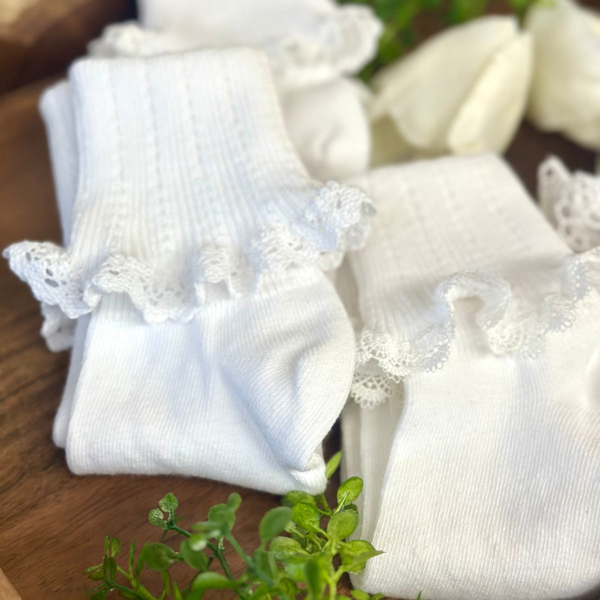 White baby socks with lace trim on a wooden surface. Valued priced 3 pair bundle assorted laces