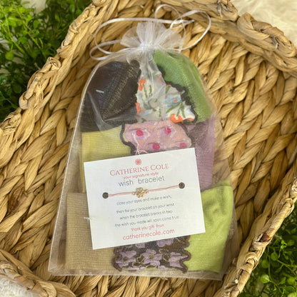 Catherine Cole wish bracelet packaging with a tag on a woven surface